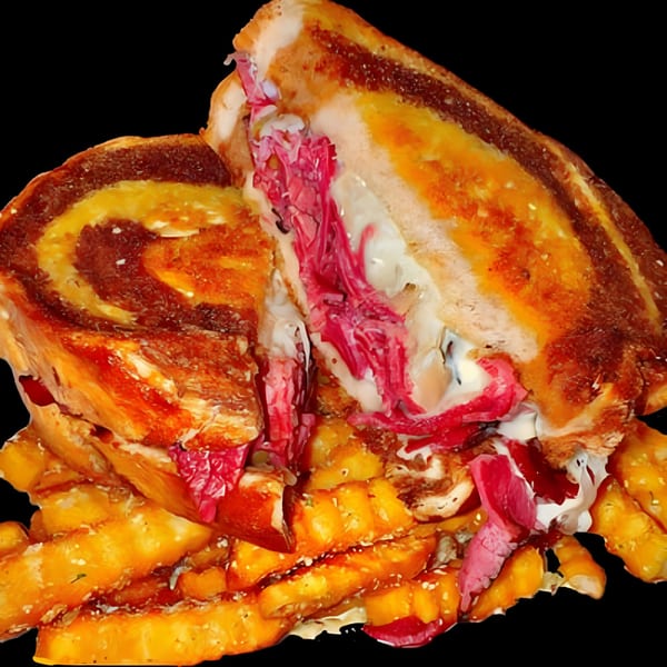 A grilled cheese sandwich with pink meat and white sauce, served with golden fries.