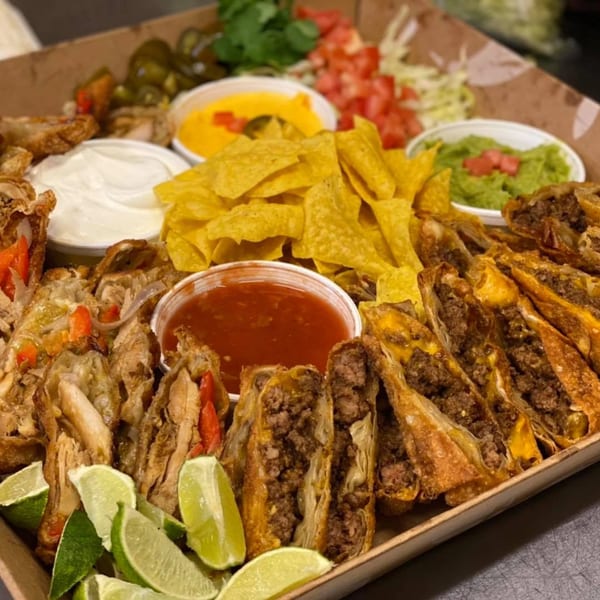A platter of Main Event Grill East's American appetizers, including egg rolls, chips, and dips.